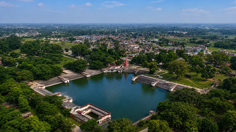 Historic ritual water tank surrounded by greenery and pilgrimage pathways