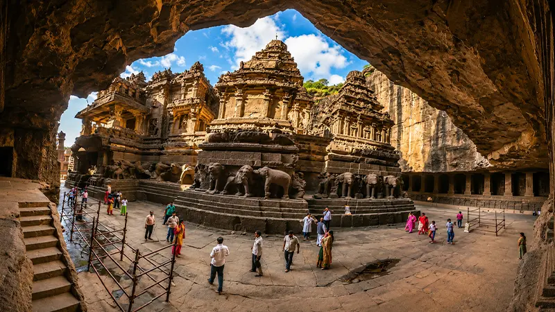 Magnificent temple ensemble viewed through a cave portal featuring elaborate stone carvings