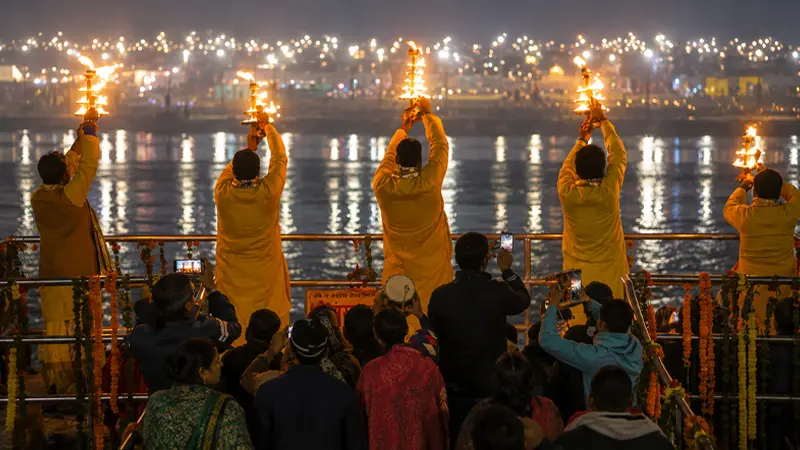 Priests performing a ceremonial fire worship ritual beside a holy river at night