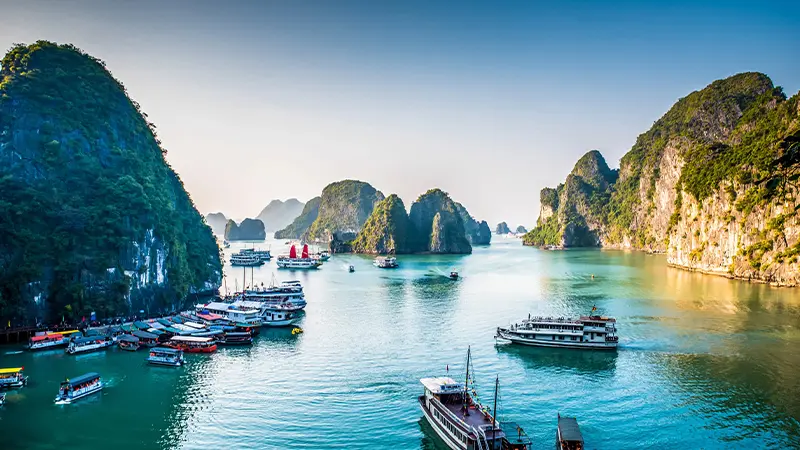 Tour boats exploring emerald waters between dramatic karst formations
