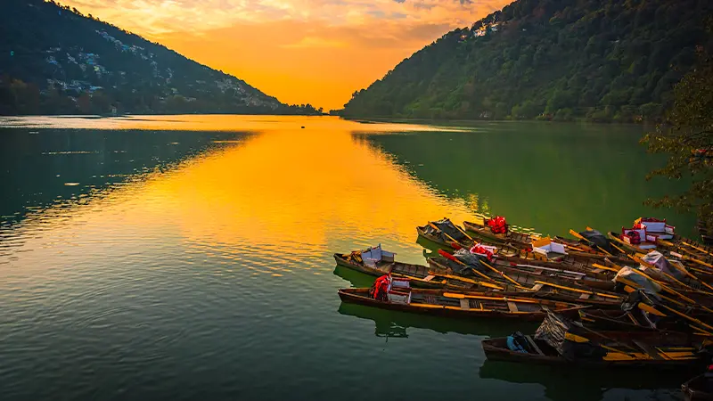 Wooden boats resting along a tranquil mountain lake at sunset