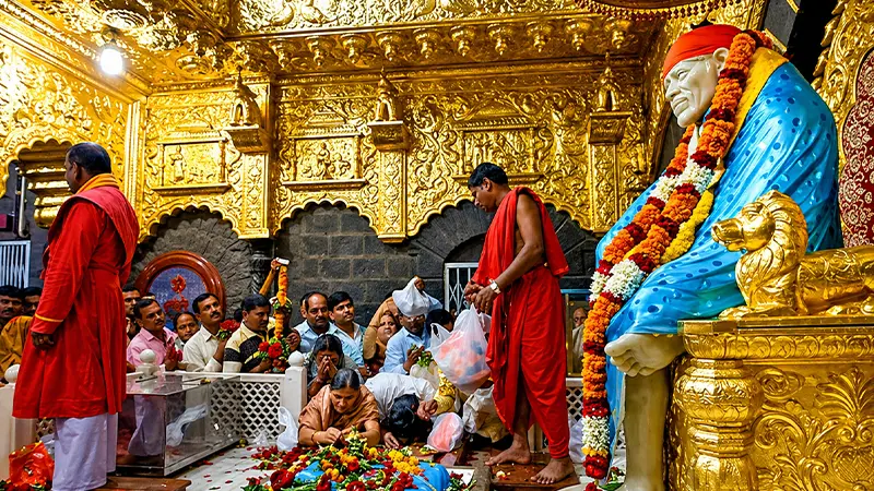 Devotees offering prayers inside a golden saint reverence chamber adorned with intricate artwork
