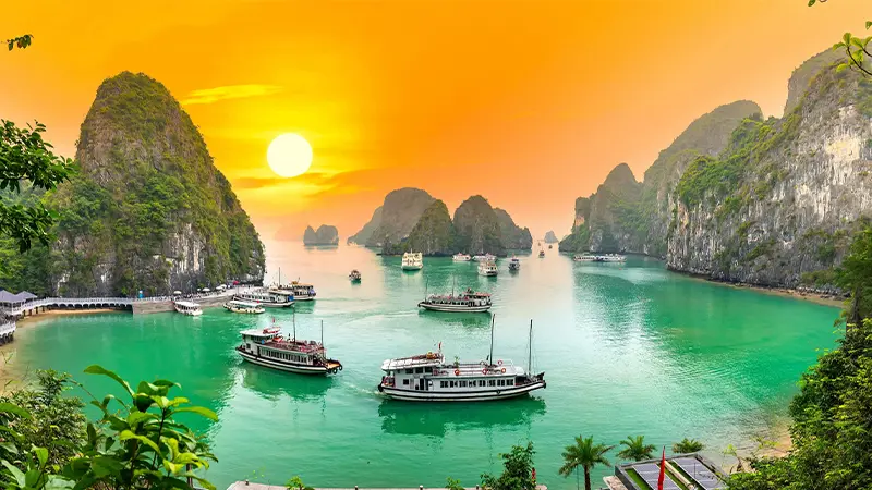 Cruise boats sailing among limestone islands at sunset in northern Vietnam