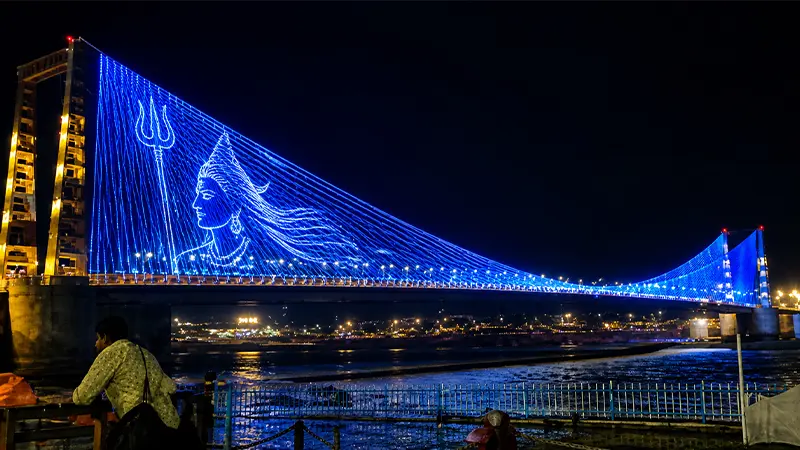 Suspension bridge decorated with colorful lights over a river at night