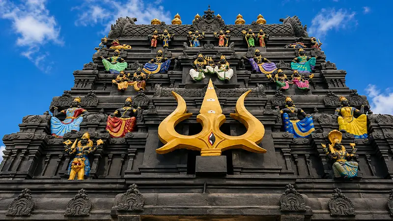 Black stone Mahakaleshwar temple facade with trishul motif and colorful deity sculptures