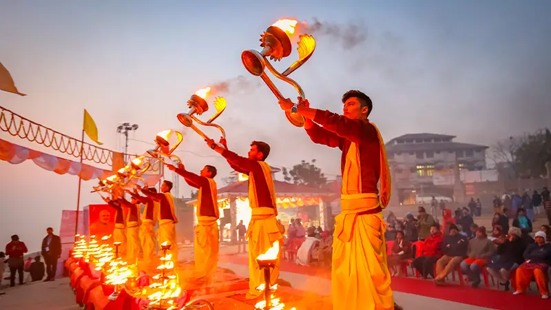 Priests performing a sacred lamp offering ceremony before devotees at dusk