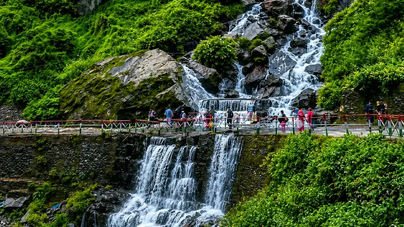 Pilgrims walking near Vasudhara Falls on the Badrinath route