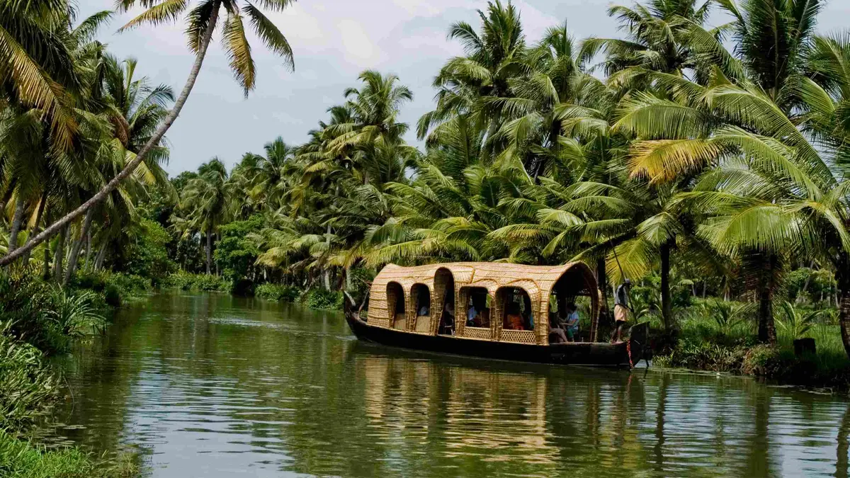 Traditional houseboat sailing through the palm-lined canals of Alleppey backwaters