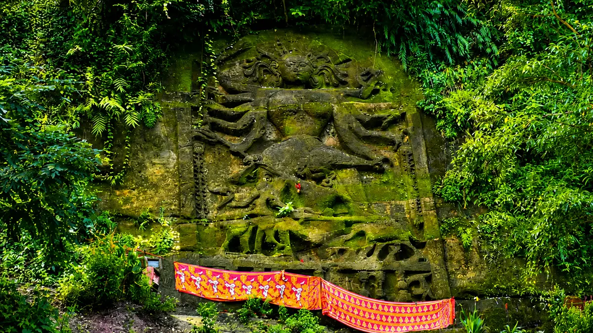 Ancient hillside rock sculptures surrounded by lush greenery in northeastern India