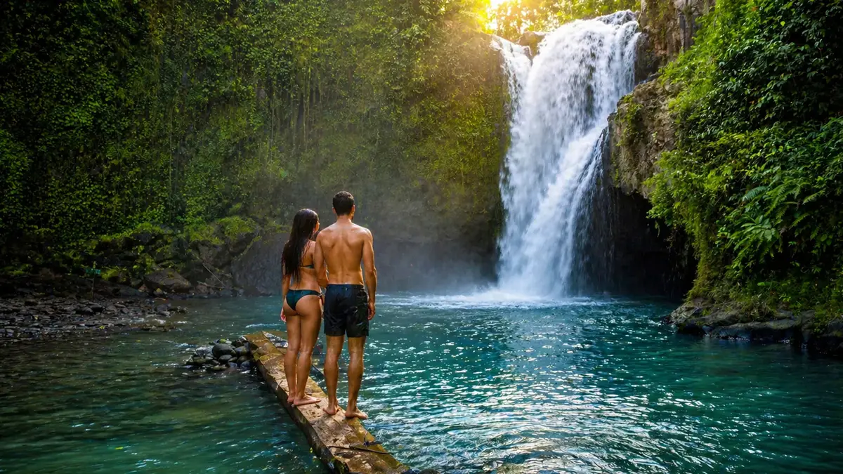 Couple admiring a hidden jungle waterfall surrounded by lush tropical forest in Bali