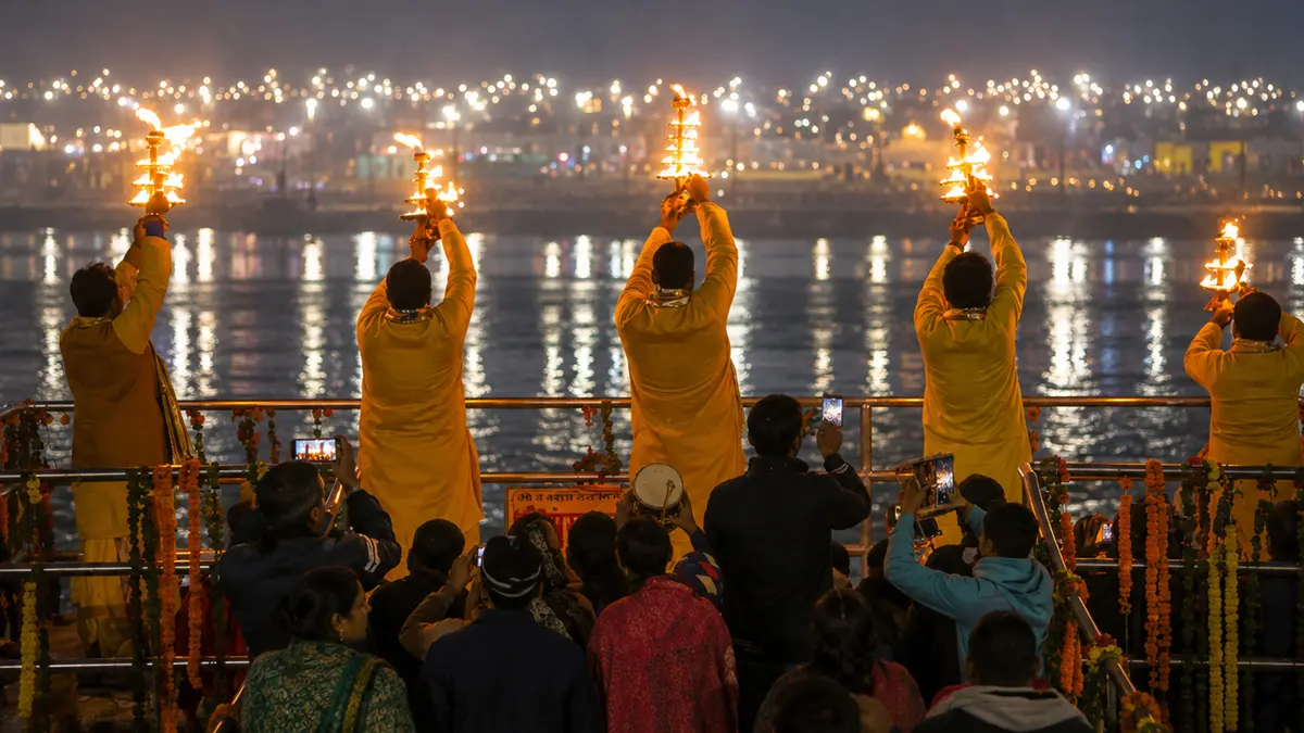 Priests performing a ceremonial fire worship ritual beside a holy river at night