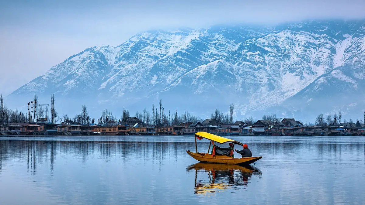 Shikara boat cruising on Dal Lake with snow-capped Himalayan peaks