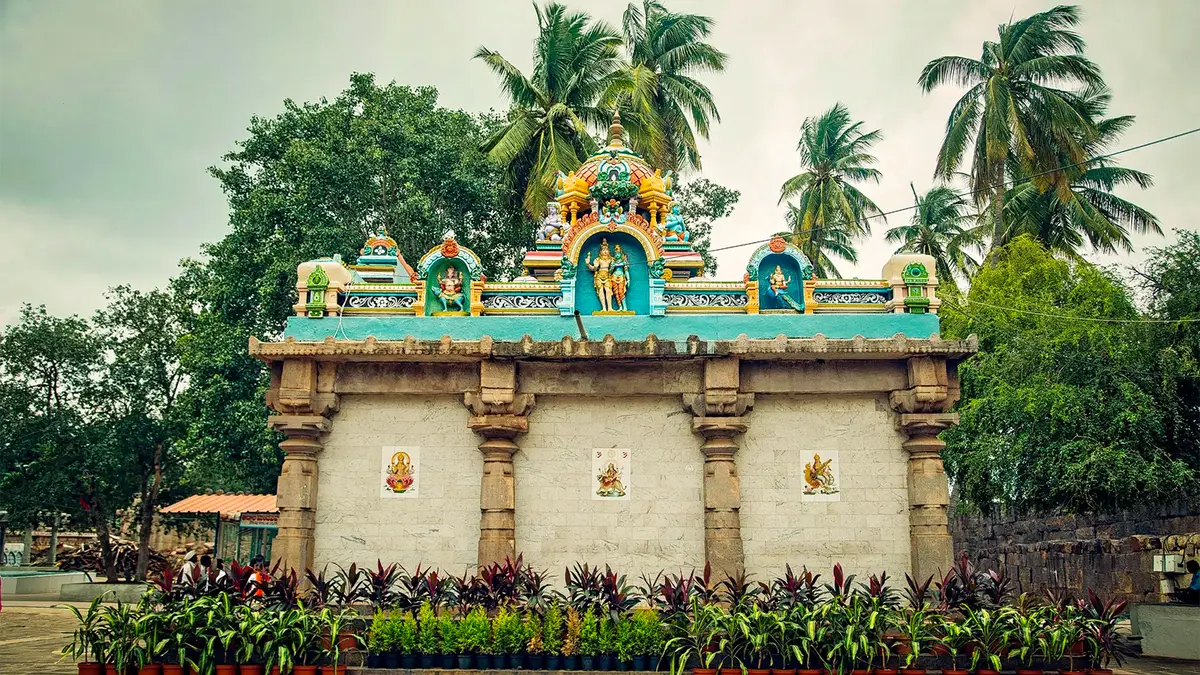 Traditional Dravidian shrine pavilion surrounded by lush gardens and palm trees