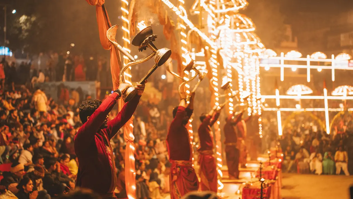 Priests performing a traditional evening ritual beside a crowded riverfront