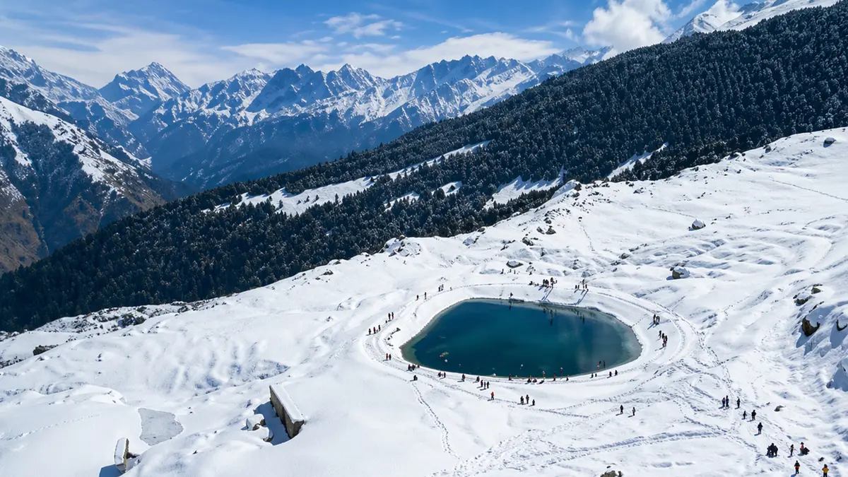 Snow-covered alpine landscape featuring a frozen circular waterbody