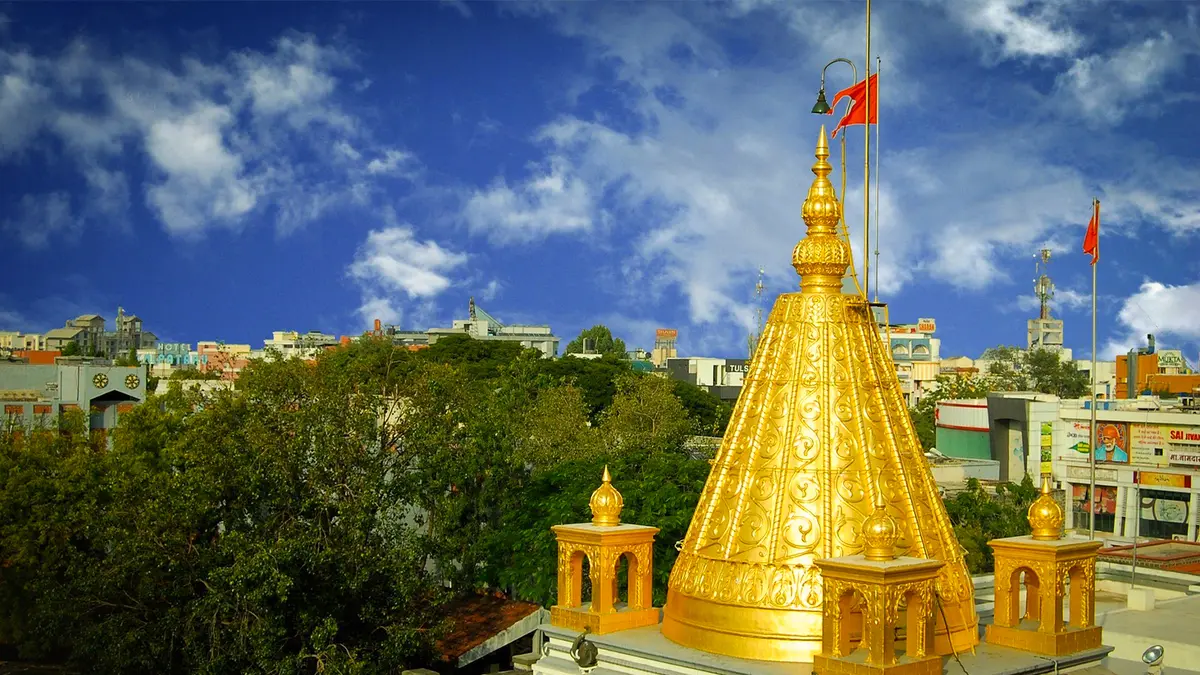 Gilded worship spire rising above the city skyline against a bright blue sky