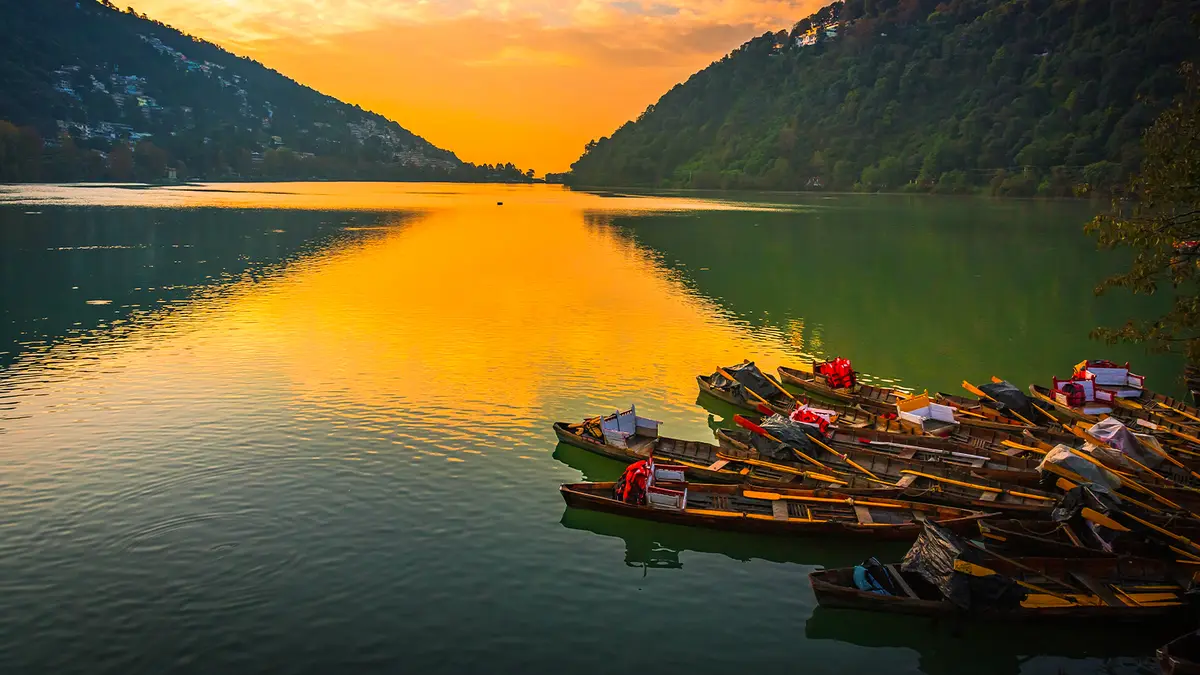 Wooden boats resting along a tranquil mountain lake at sunset