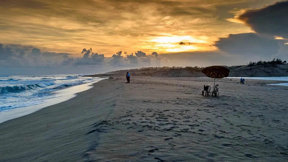 Golden sunset casting warm light across a tranquil sandy shoreline