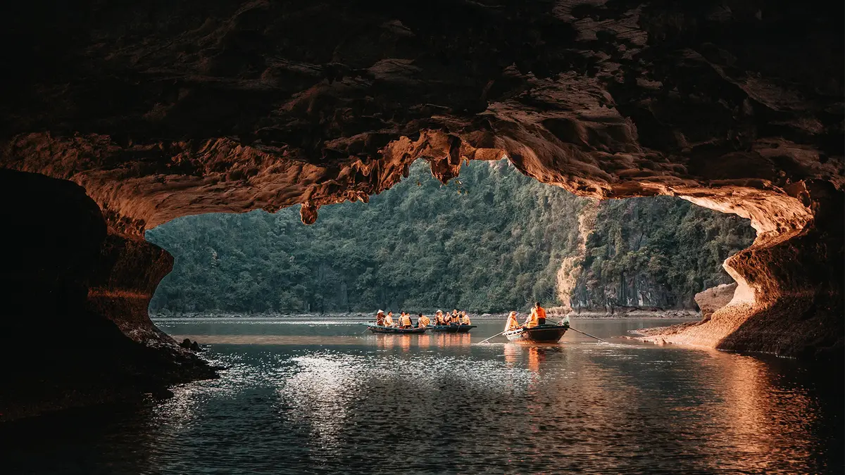 Visitors exploring a limestone cave by boat through tranquil waters