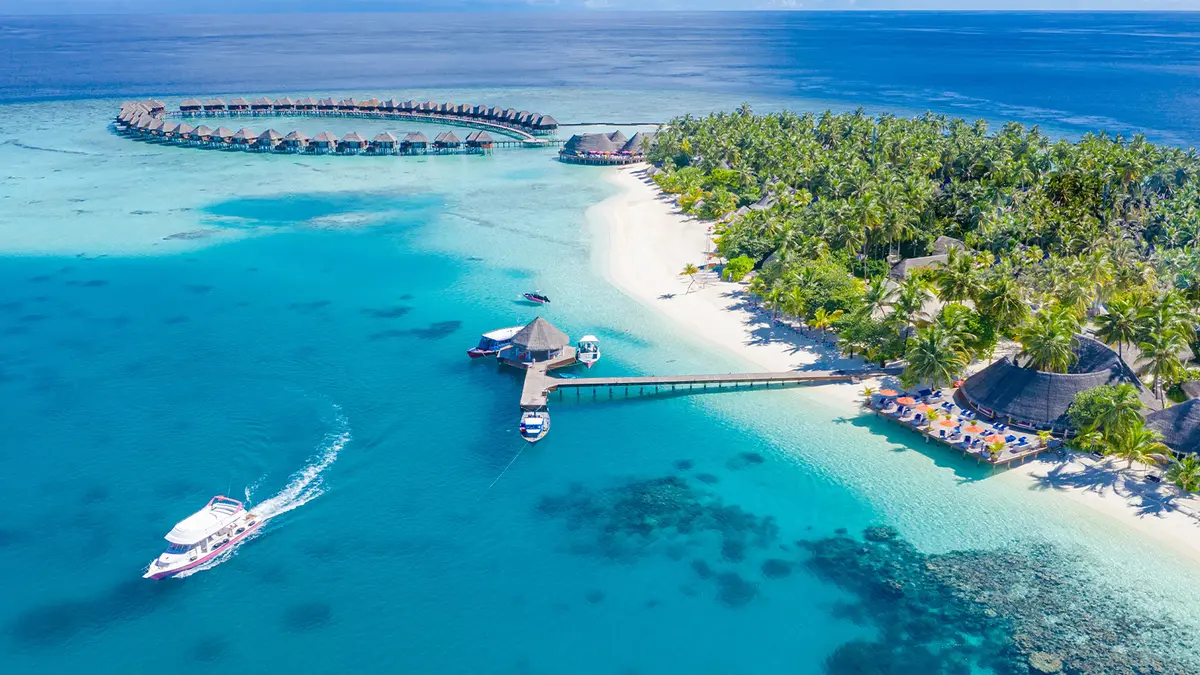 Aerial view of a tropical Maldives island resort with overwater villas