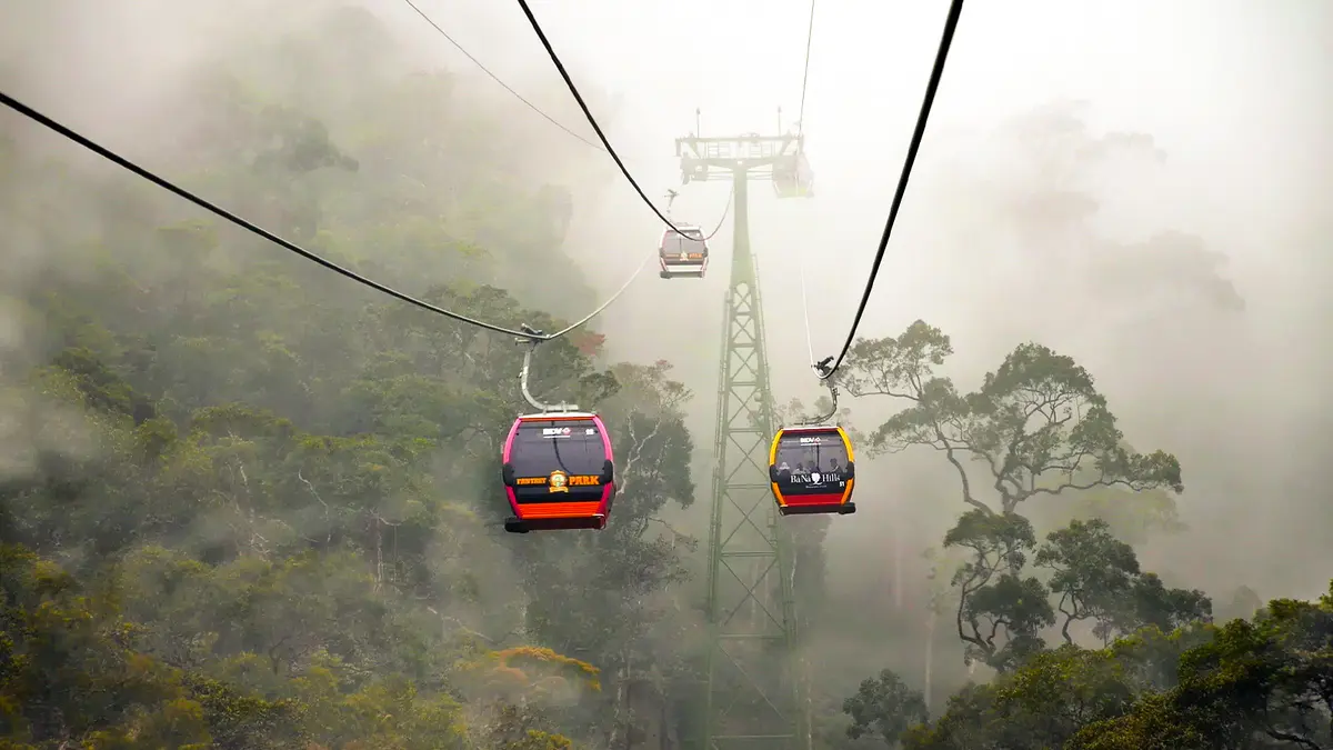 Cable cars gliding through mist covered forested hills in Vietnam