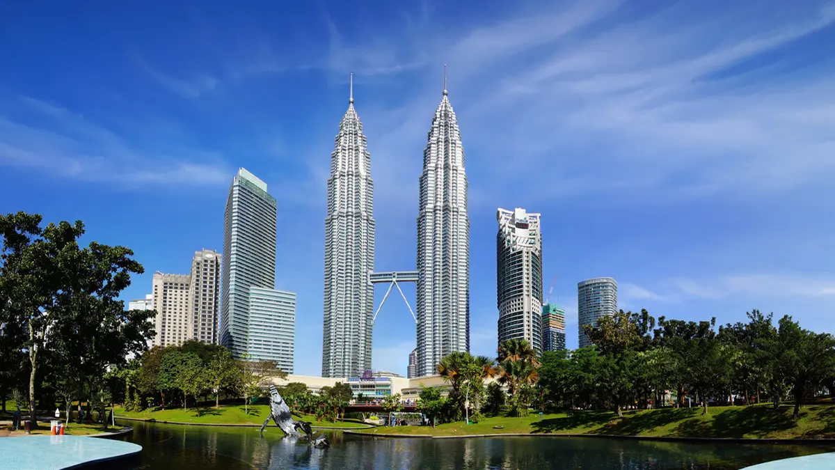 Petronas Twin Towers rising above Kuala Lumpur city skyline with landscaped park foreground