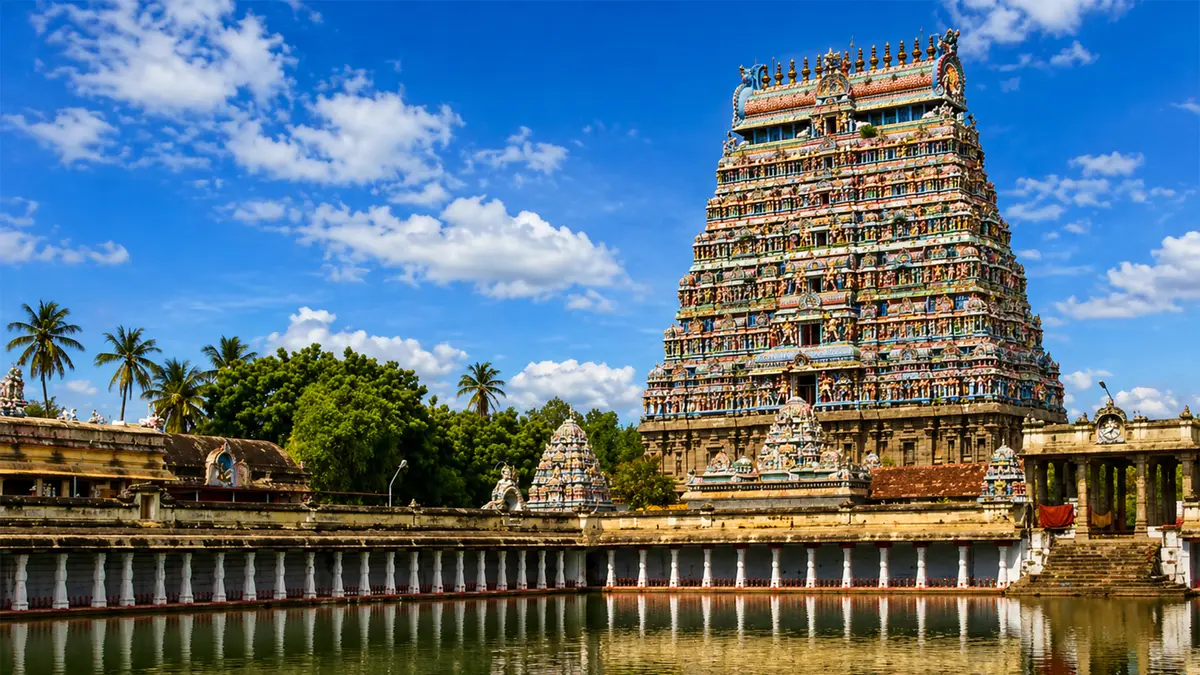 Colorful temple tower reflected in a sacred water tank surrounded by shrines