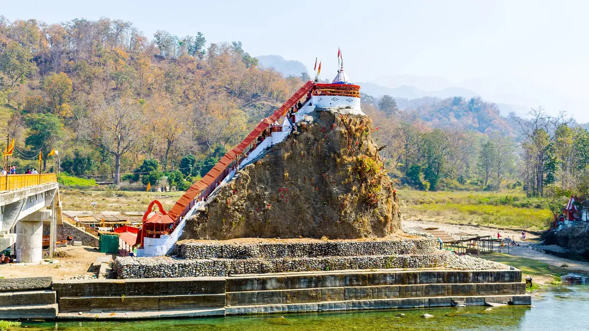 Ancient rock shrine accessed by stairway beside a river landscape