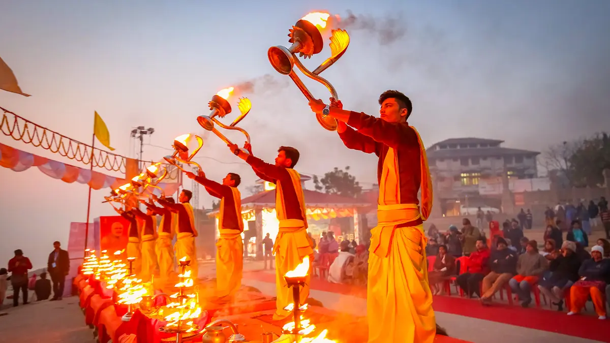 Priests performing a sacred lamp offering ceremony before devotees at dusk