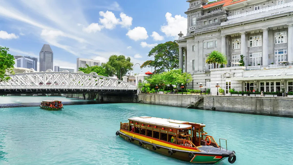 Traditional river cruise boat sailing along the Singapore River beside heritage landmarks